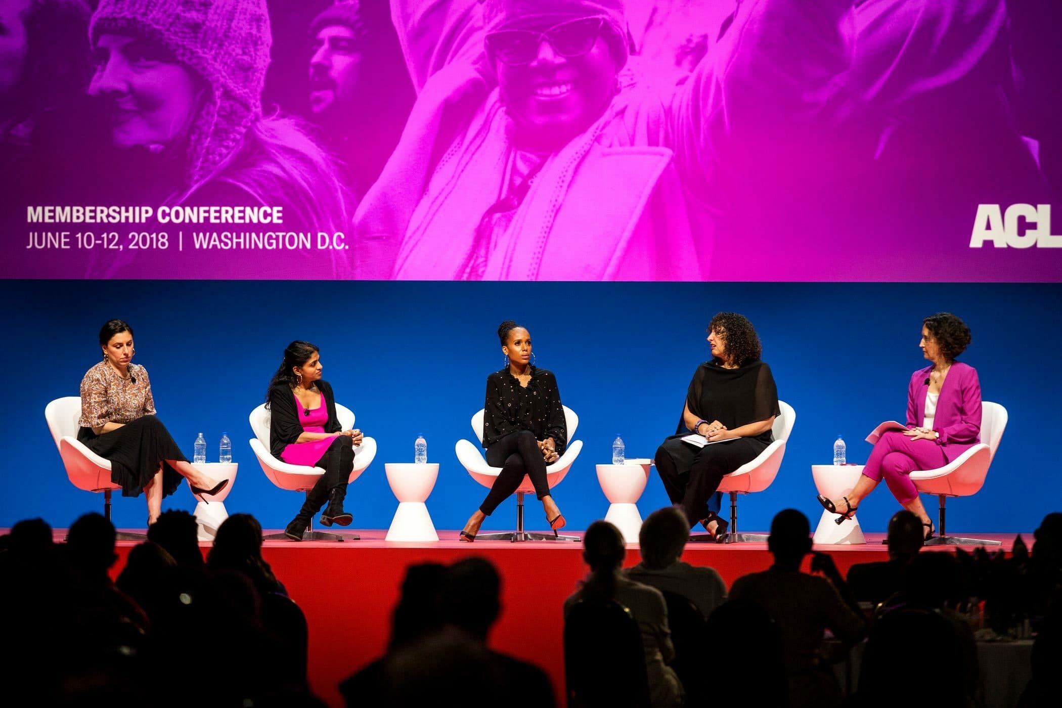 A panel of five women sits on a stage during a conference. The backdrop has a large image of a woman and reads "Membership Conference, June 10-12, 2018, Washington D.C." The audience is visible in the foreground.