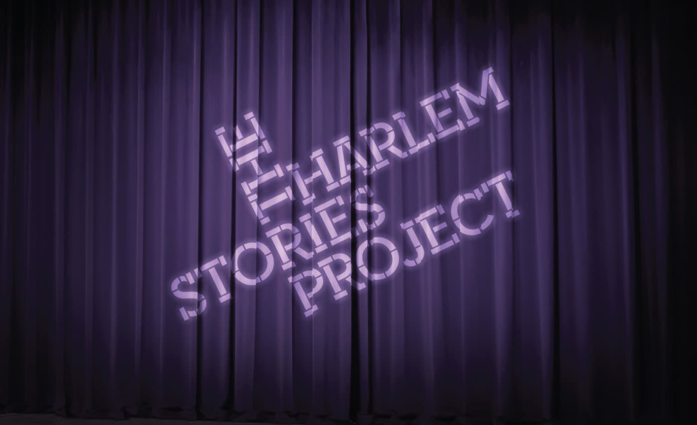 A purple curtain with the words “The Harlem Stories Project” projected onto it in white lettering. The text has a diagonal slant from the bottom right to the top left. The curtain has vertical folds and drapes down to the floor.