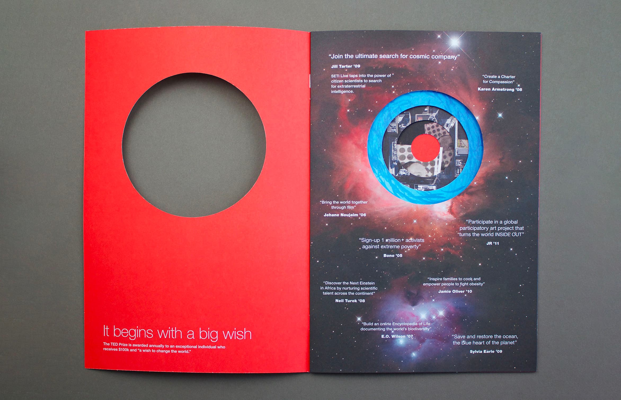 A two-page brochure on a dark gray surface. The left page is red with a large circular cutout and reads "It begins with a big wish." The right page has a cosmic background with a circular image of the Earth, overlaid with various white text quotes about space exploration.