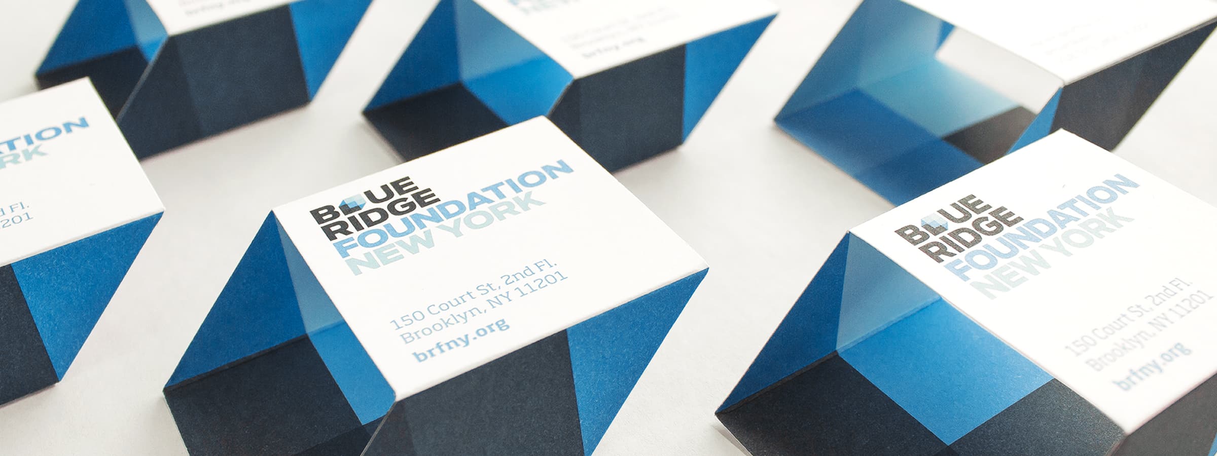 The image shows multiple blue and white boxes with the text "BLUE RIDGE FOUNDATION NEW YORK" and the URL "brfny.org". Additionally, there is an address: "150 Court St., 2nd Fl., Brooklyn, NY 11201". The boxes are arranged in a repetitive, neat pattern.