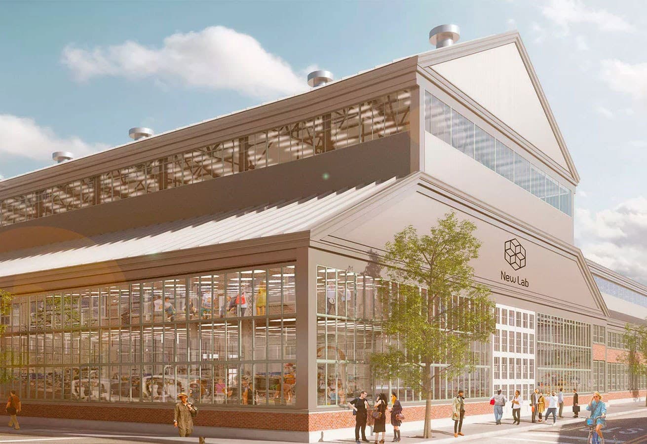 A modern industrial building with large glass windows and a geometric logo labeled "New Lab" on the facade. People are gathered outside, and the building's design features a mix of metal and glass with several floors visible inside.