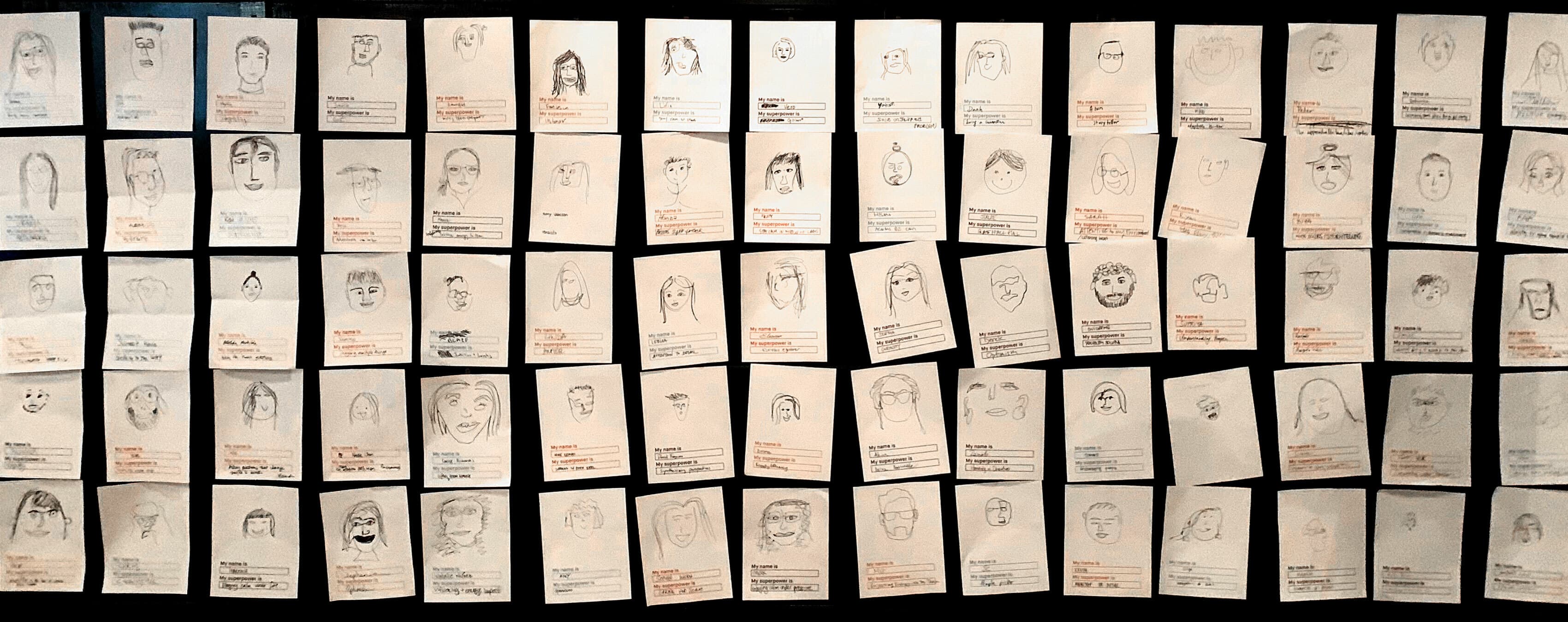 A wall displays numerous hand-drawn sketches of faces on individual pieces of paper. The drawings vary in style and detail, each accompanied by handwritten notes in different colors. The arrangement is orderly, with sketches pinned or taped in a grid-like pattern.