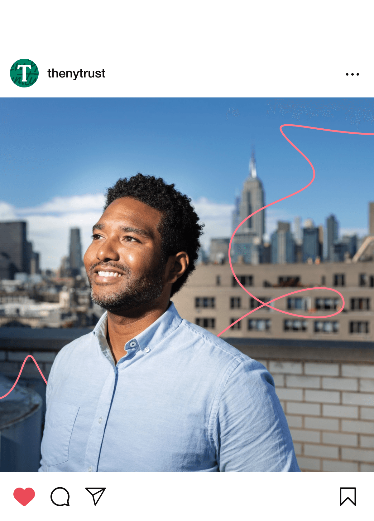 A man with short curly hair and a beard smiles while standing on a rooftop with a city skyline, including the Empire State Building, in the background. He is wearing a light blue button-up shirt. The sky is clear, and a red squiggly line is drawn on the image.