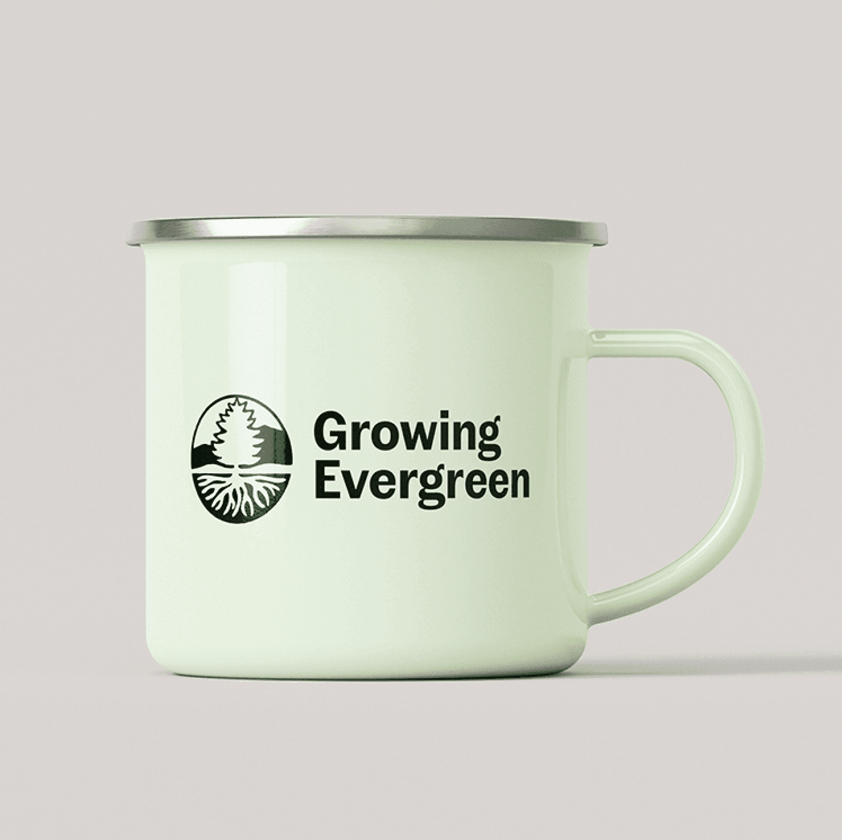 A light green enamel mug with a silver rim features a logo of a tree and the text "Growing Evergreen" in black. The mug is placed against a plain beige background.