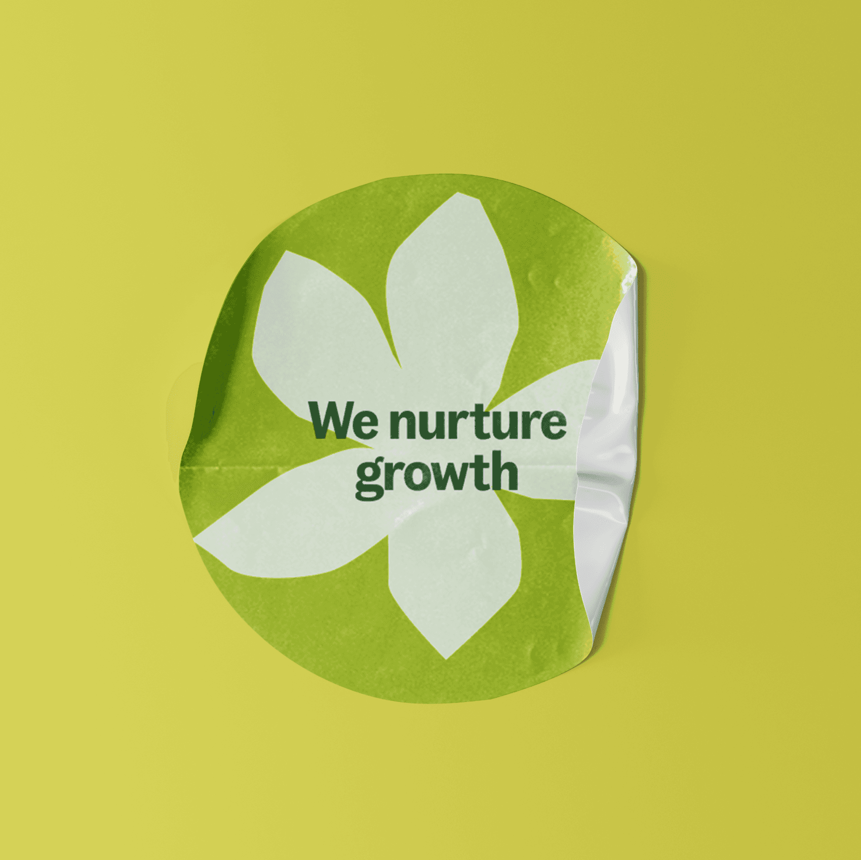 A crumpled, circular green sticker on a yellow background features a white flower graphic with the text "We nurture growth" printed in the center.