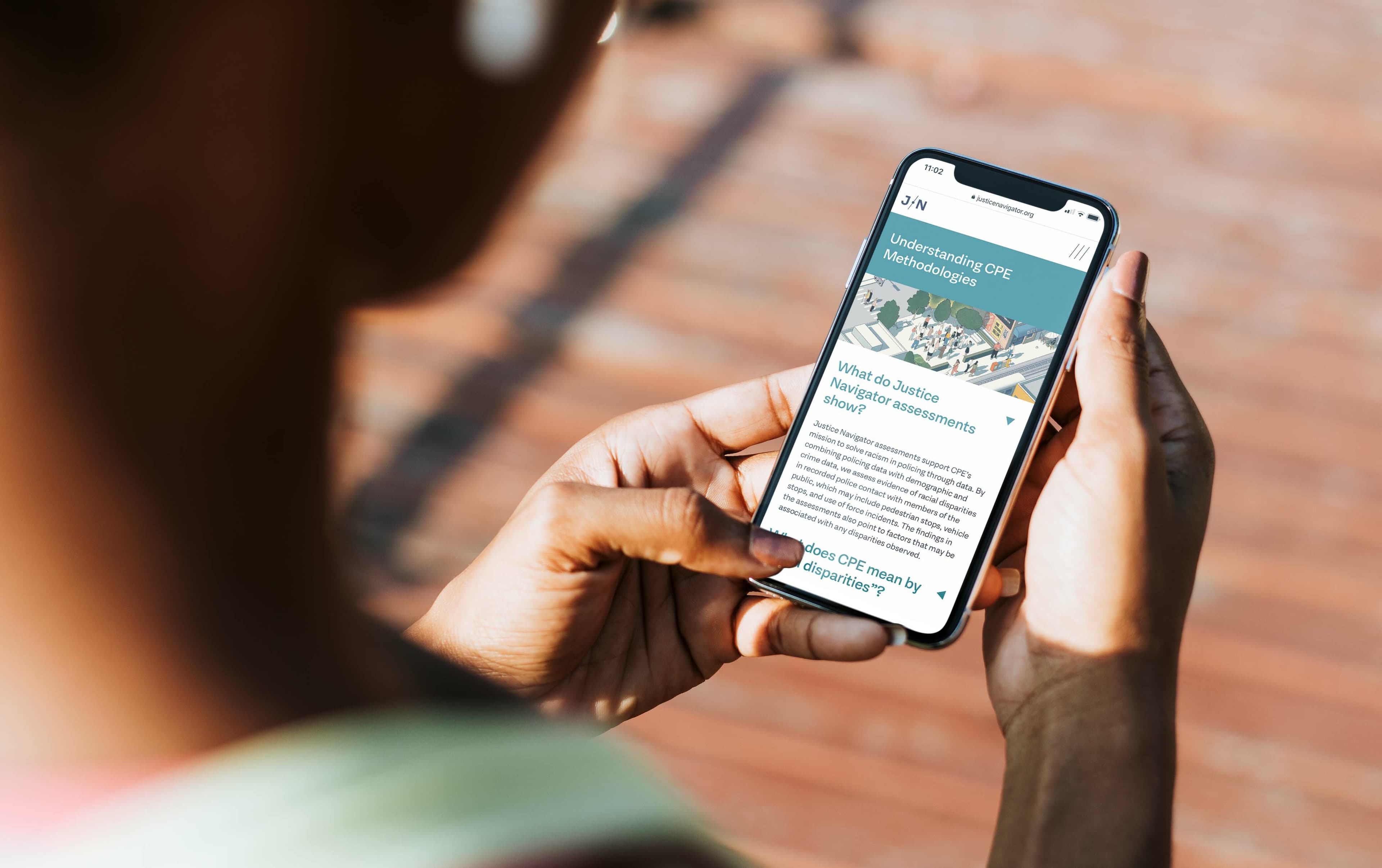 A person holds a smartphone, reading an article titled "Understanding CPE Methodologies." The screen displays text and an image related to business strategy assessments. The person's hands and part of their face are visible in the foreground.