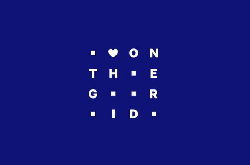 A blue background with a grid arrangement of white squares, where each square contains a letter. The letters spell out the phrase "ON THE GRID," with a heart symbol in the top left corner.