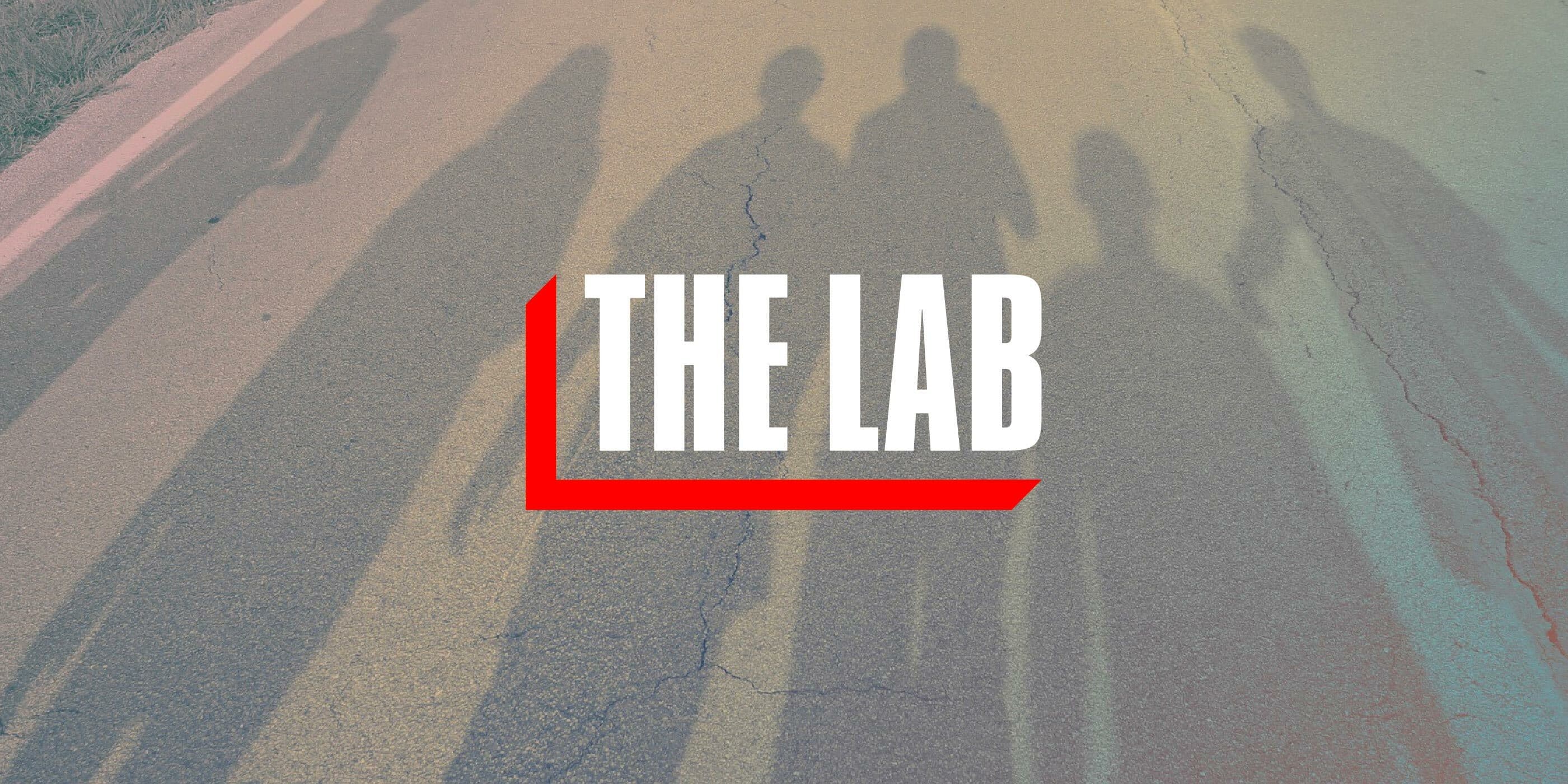 Shadows of five people walking on a road with a gradient color effect. Large white text in the center reads "THE LAB," underlined with a red bar.
