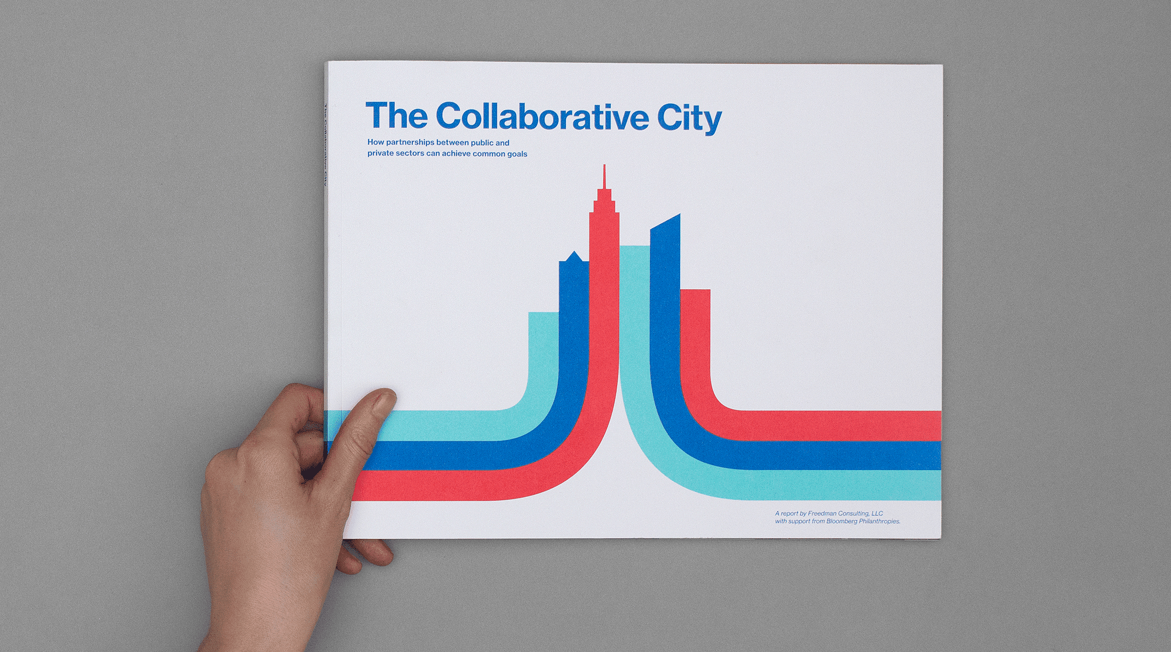 A hand holds a book titled "The Collaborative City" featuring stylized graphics of abstract buildings in blue, red, and turquoise on a gray background. The subtitle reads: "How partnerships between public and private sectors can achieve common goals.