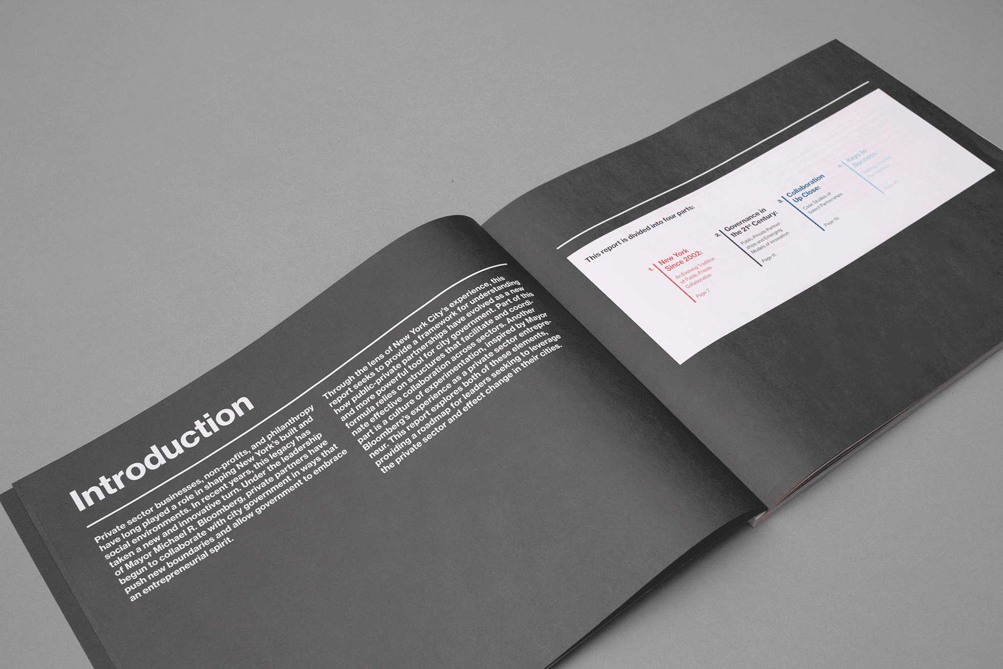 An open book with a black page on the left showing white text titled "Introduction" and a white page on the right displaying a colorful chart or table. The background is solid gray.