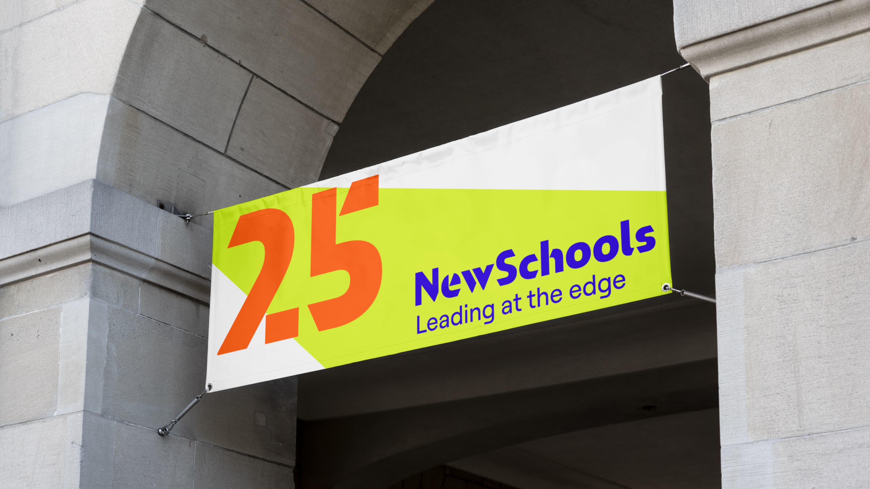 A bright banner hangs under an archway between two light gray stone columns. The banner features "2.5" in large orange text on a green and yellow background with the text "NewSchools Leading at the edge" in blue on the right side.