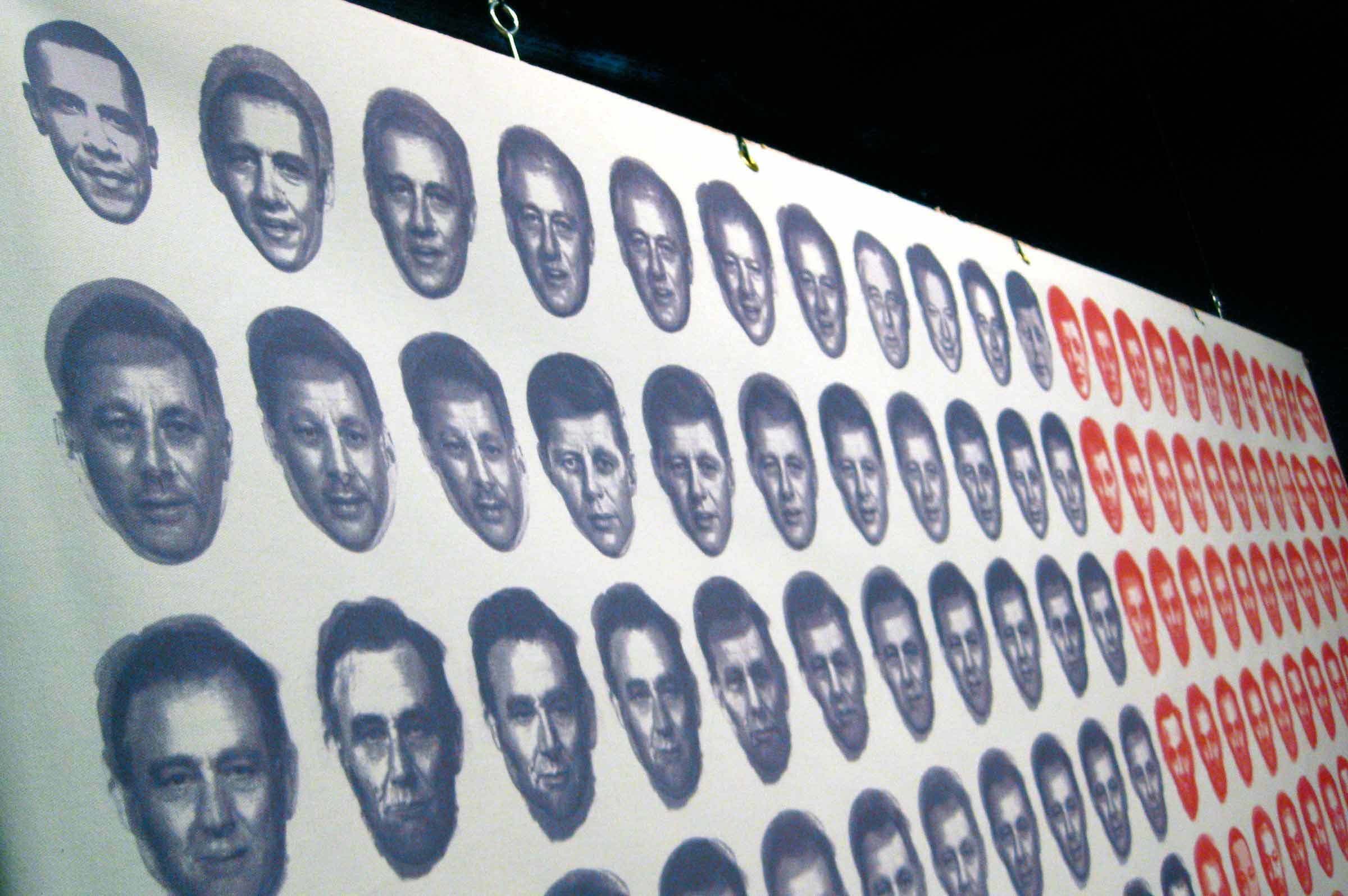 A display of numerous grayscale and red monochrome portraits of the same man's face in rows and columns on a white background. The faces show minor variations in expression and shading.