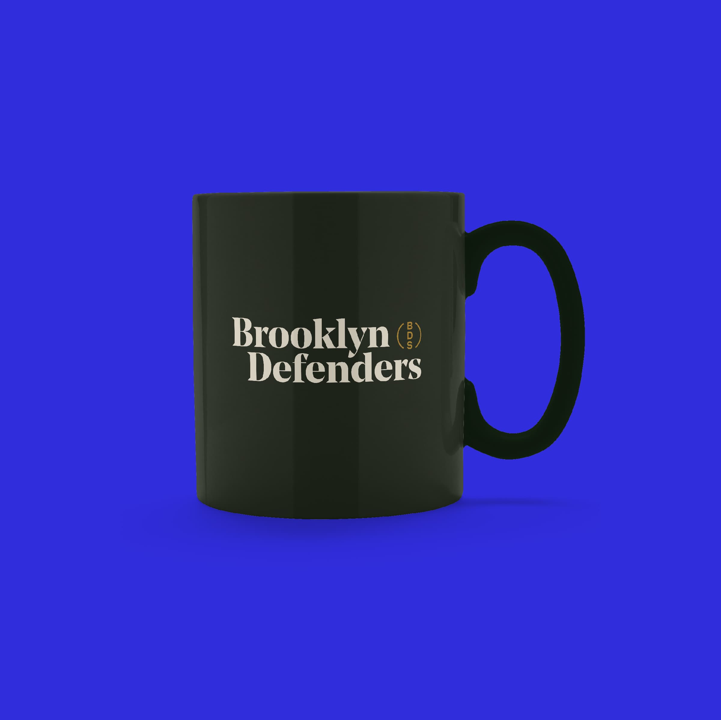 A black mug with the words "Brooklyn Defenders" printed in white is centered against a solid blue background. The mug is shown from the side, clearly displaying the text.
