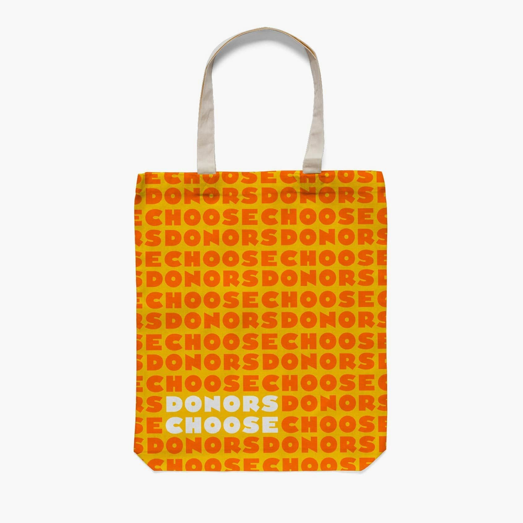 A tote bag with the text "DONORS CHOOSE" repeated in a pattern. The words "DONORS" are in red and "CHOOSE" in yellow, on an orange background. The bag has white handles, with the words "DONORS CHOOSE" in white and light blue at the bottom center.