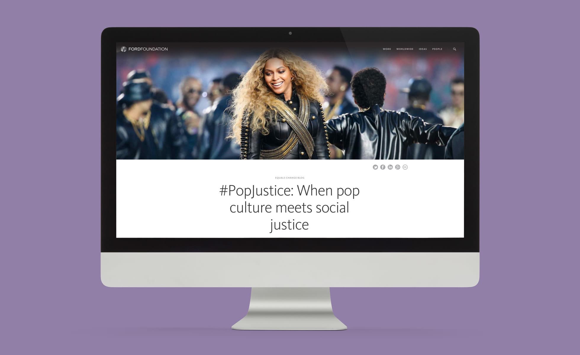 A desktop computer stands on a purple surface displaying a website featuring a smiling woman with curly hair in a fur coat. The website headline reads "#PopJustice: When pop culture meets social justice." The background features people in leather jackets.