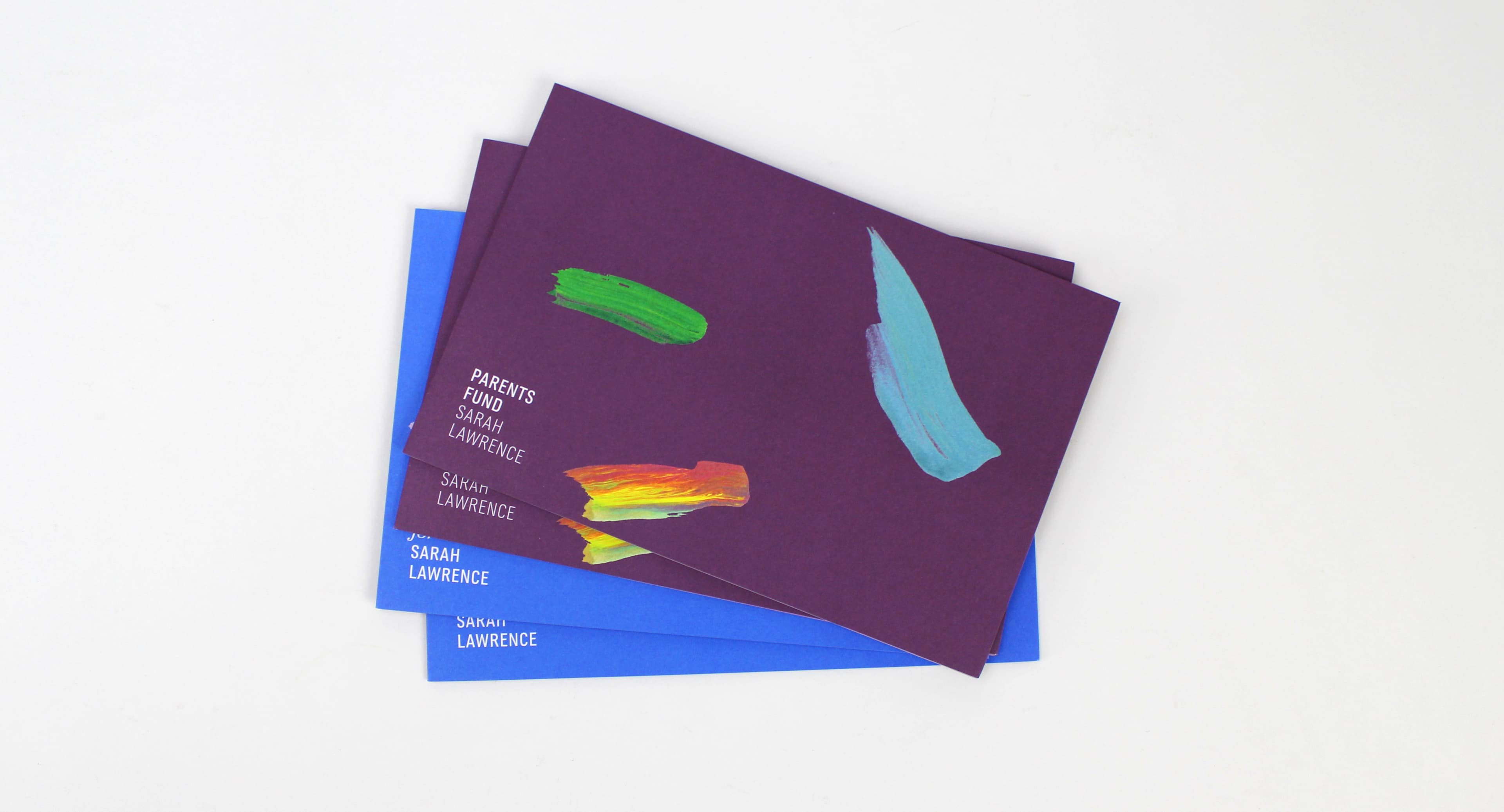 A stack of envelopes is shown, with the top two featuring abstract paint streaks. The top envelope is dark purple, has green and turquoise paint streaks, and text that reads "PARENTS FUND INVITE" and "SARAH LAWRENCE." The bottom envelope is blue with "SARAH LAWRENCE" text.