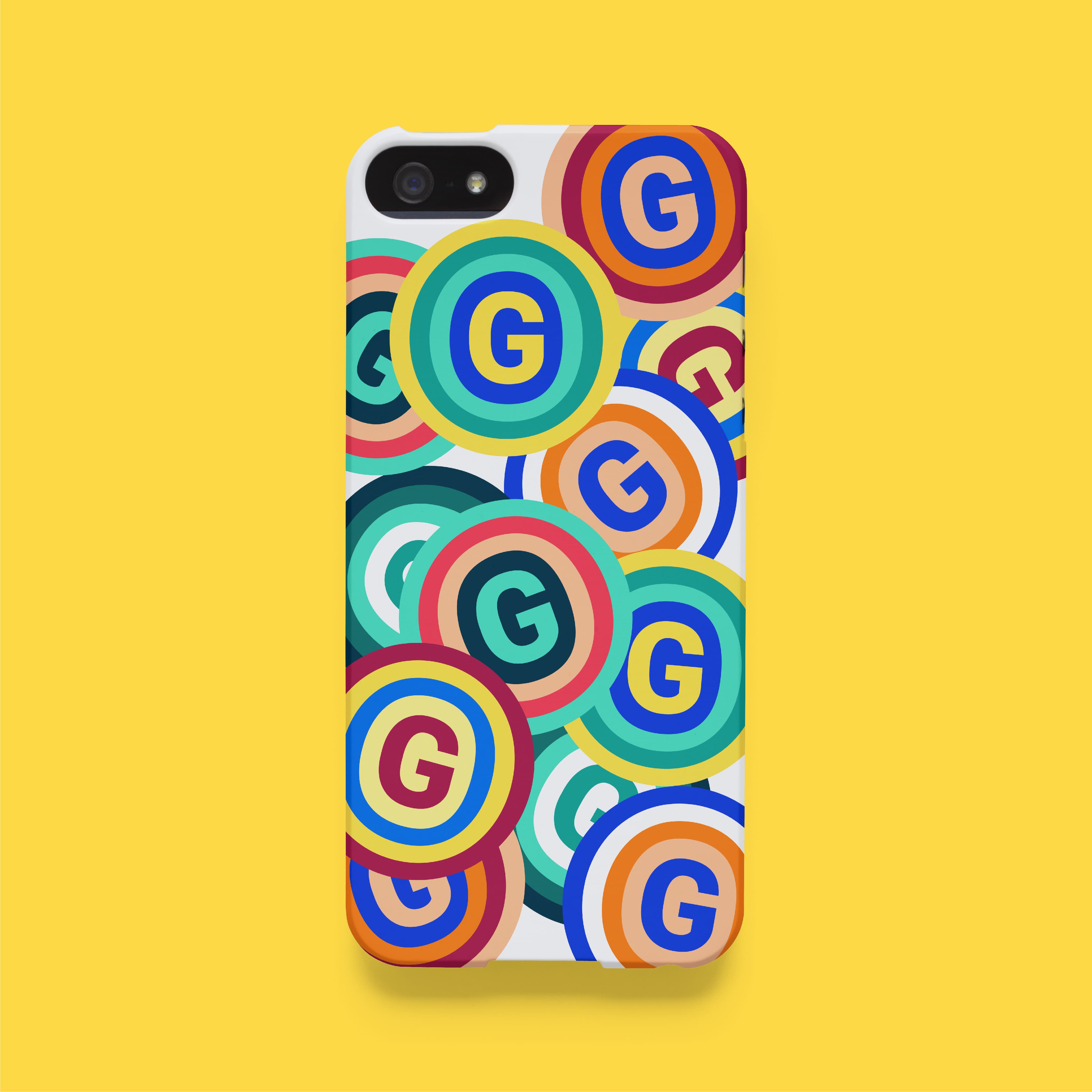 A smartphone with a case featuring a pattern of colorful concentric circles, each with a prominent "G" in the center. The background is yellow, highlighting the vibrant design of the phone case.