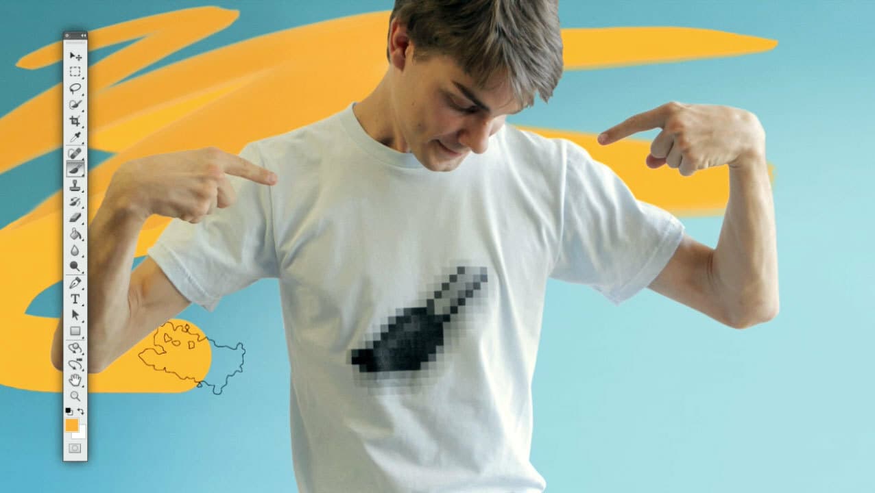 A person with short hair is wearing a white t-shirt with a pixelated graphic on the front, pointing at the graphic with both hands. The background features abstract yellow and blue brush strokes along with a tool palette from graphic design software.