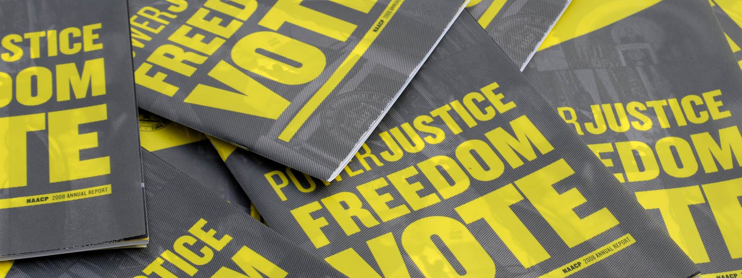 A stack of pamphlets with bold yellow text on black backgrounds. The text reads "POWER. JUSTICE. FREEDOM. VOTE." and "NAACP 2020 ANNUAL REPORT." The pamphlets overlap each other, partially obscuring some of the text.