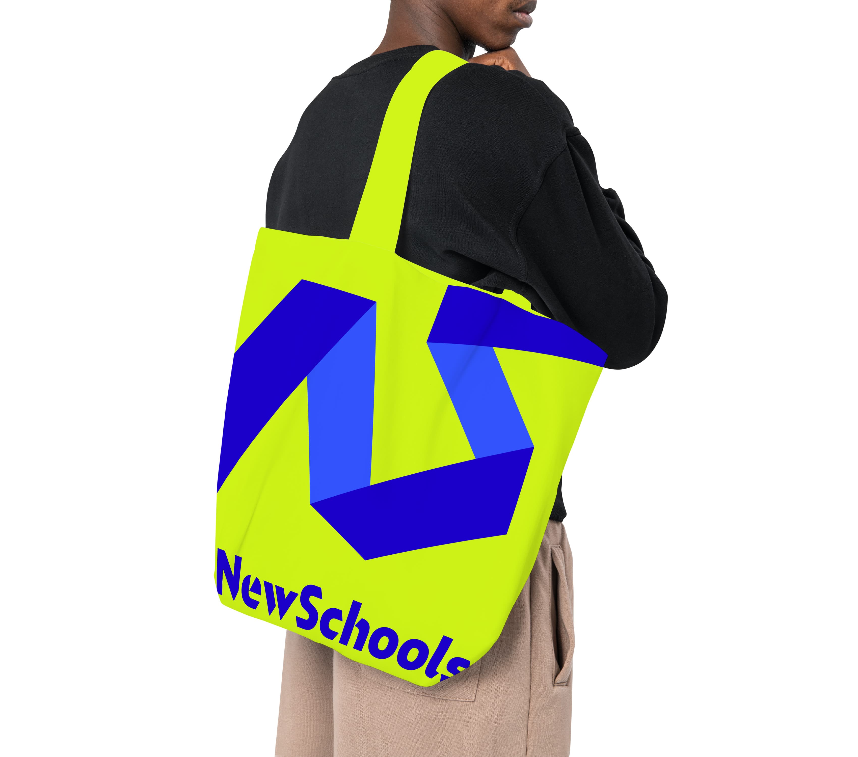 A person wearing a black shirt and beige pants is carrying a neon yellow tote bag with a bold blue geometric design and the text "NewSchools" in blue at the bottom of the bag. The person is partially turned away from the camera.