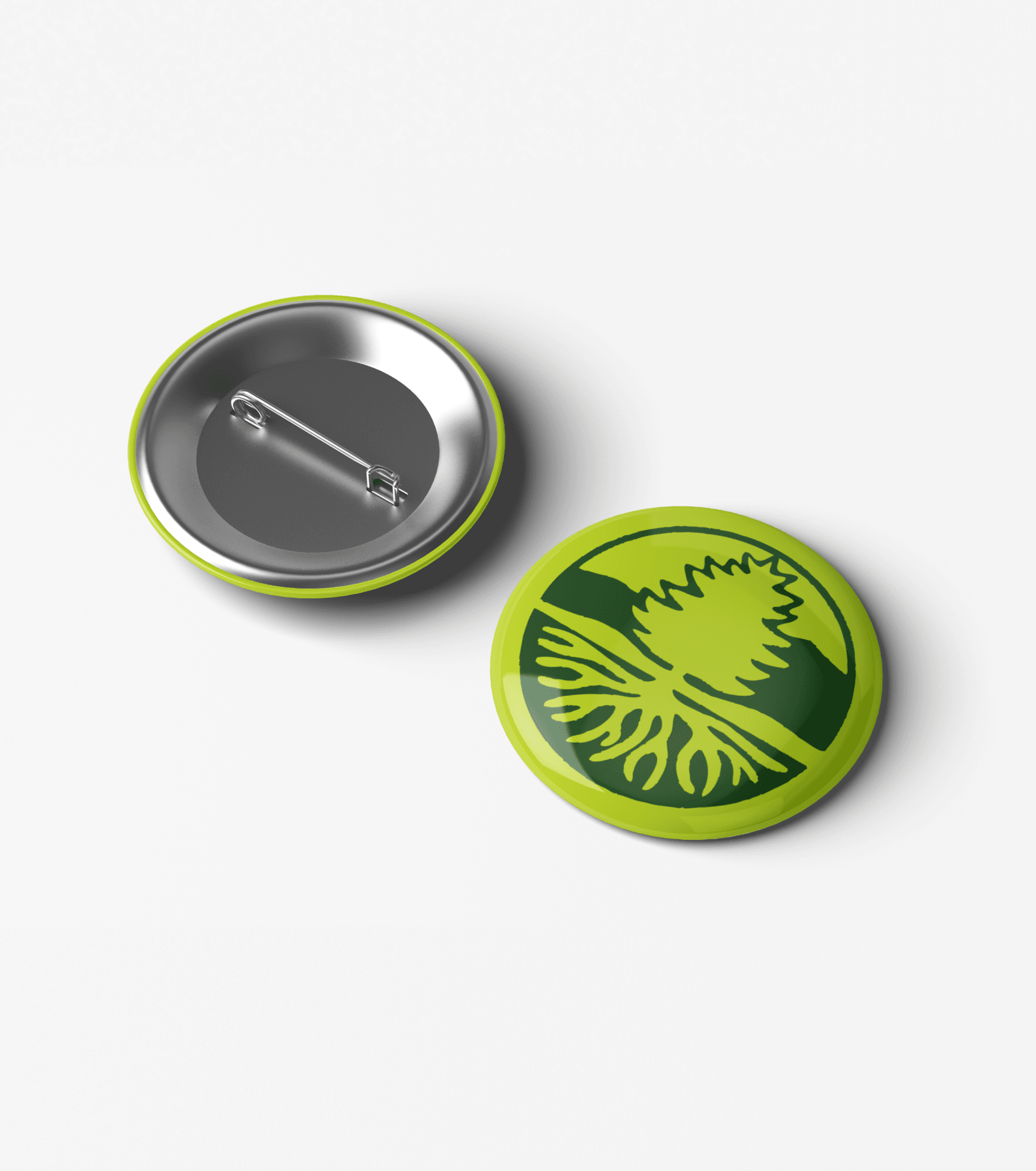 Two green pins with silver backs are displayed. One pin shows a stylized dandelion design on a green background, while the other pin is flipped to reveal its pin mechanism.