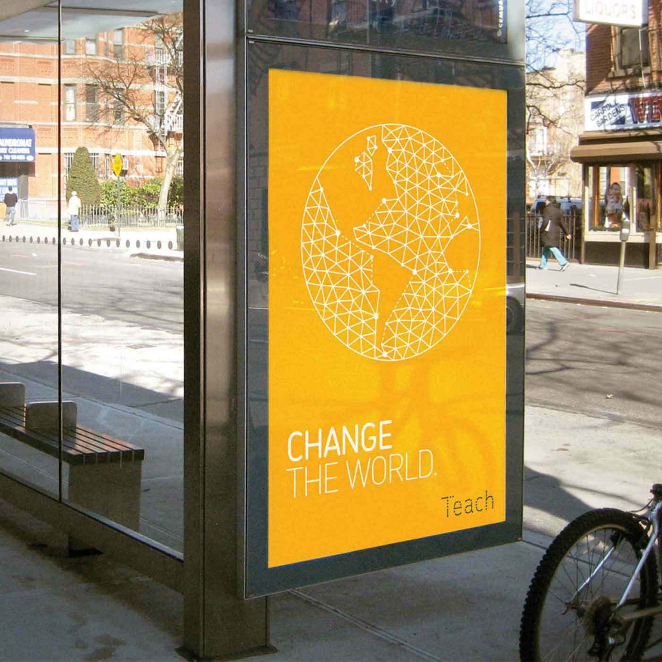 A bus stop ad in a city displays a bright yellow poster with a geometric globe illustration and the text "CHANGE THE WORLD" in white, and "Teach" in smaller white text at the bottom. Nearby, buildings and a bicycle are partially visible.