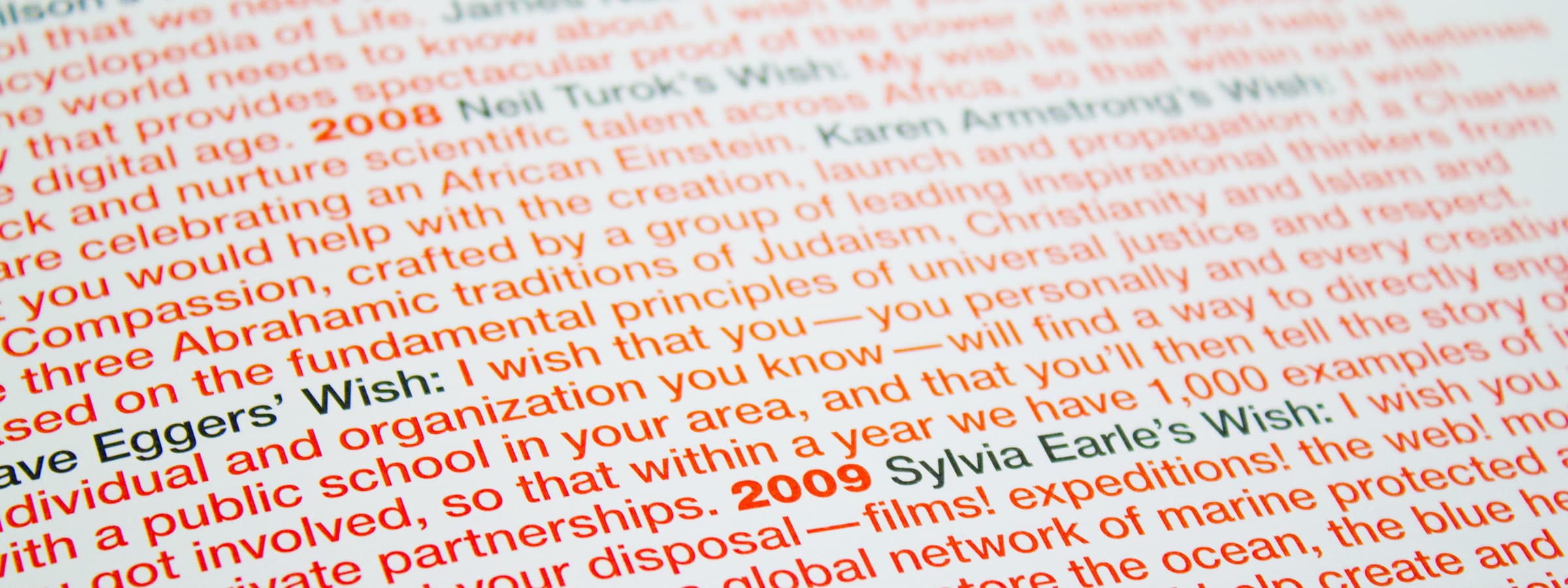Close-up of a printed page showing text in orange and black. The text contains years such as 2008 and 2009, with names like Neil Turok and Sylvia Earle, and words about fundamental principles, justice, compassion, and schools.