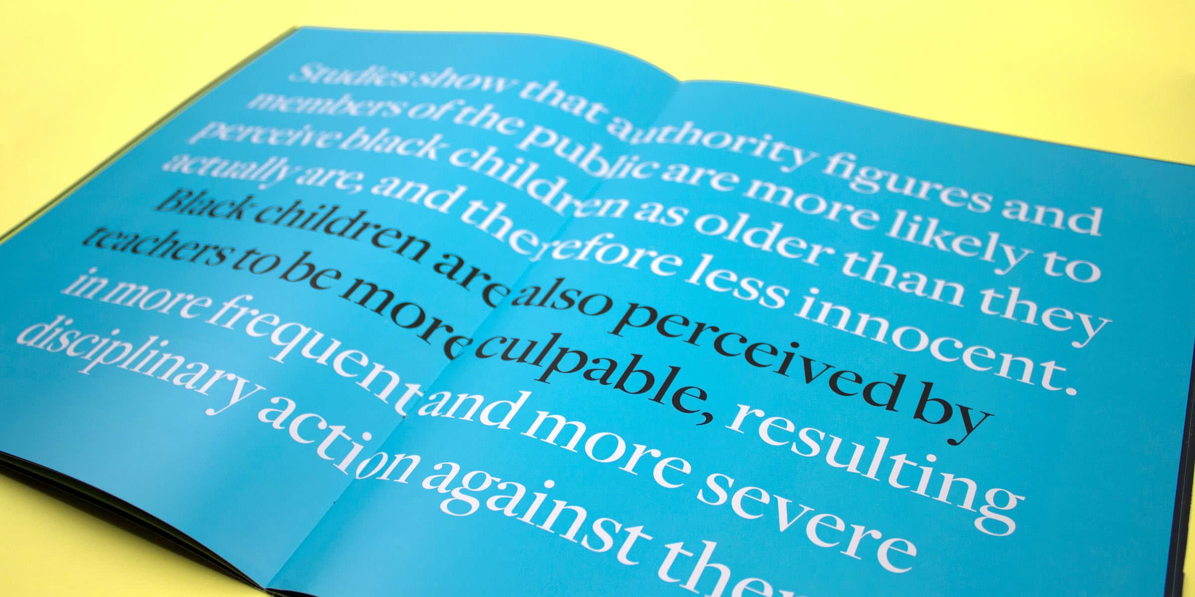 An open book with a blue background displays white text discussing the perception of black children as older and less innocent by authority figures and the public, leading to teachers perceiving them as more culpable and subjecting them to more severe disciplinary actions.