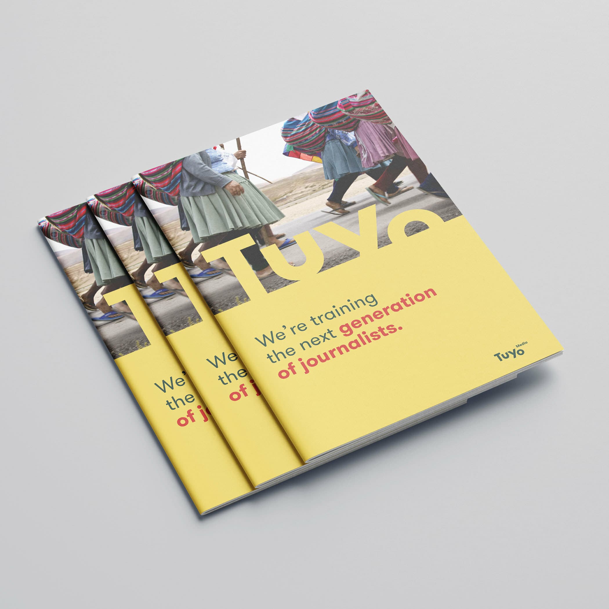 Three copies of a magazine are laid out slightly overlapping. The cover features an image of people walking, legs visible, with the bold text "We're training the next generation of journalists" on a yellow background. The word "Tuyo" appears on the bottom right.