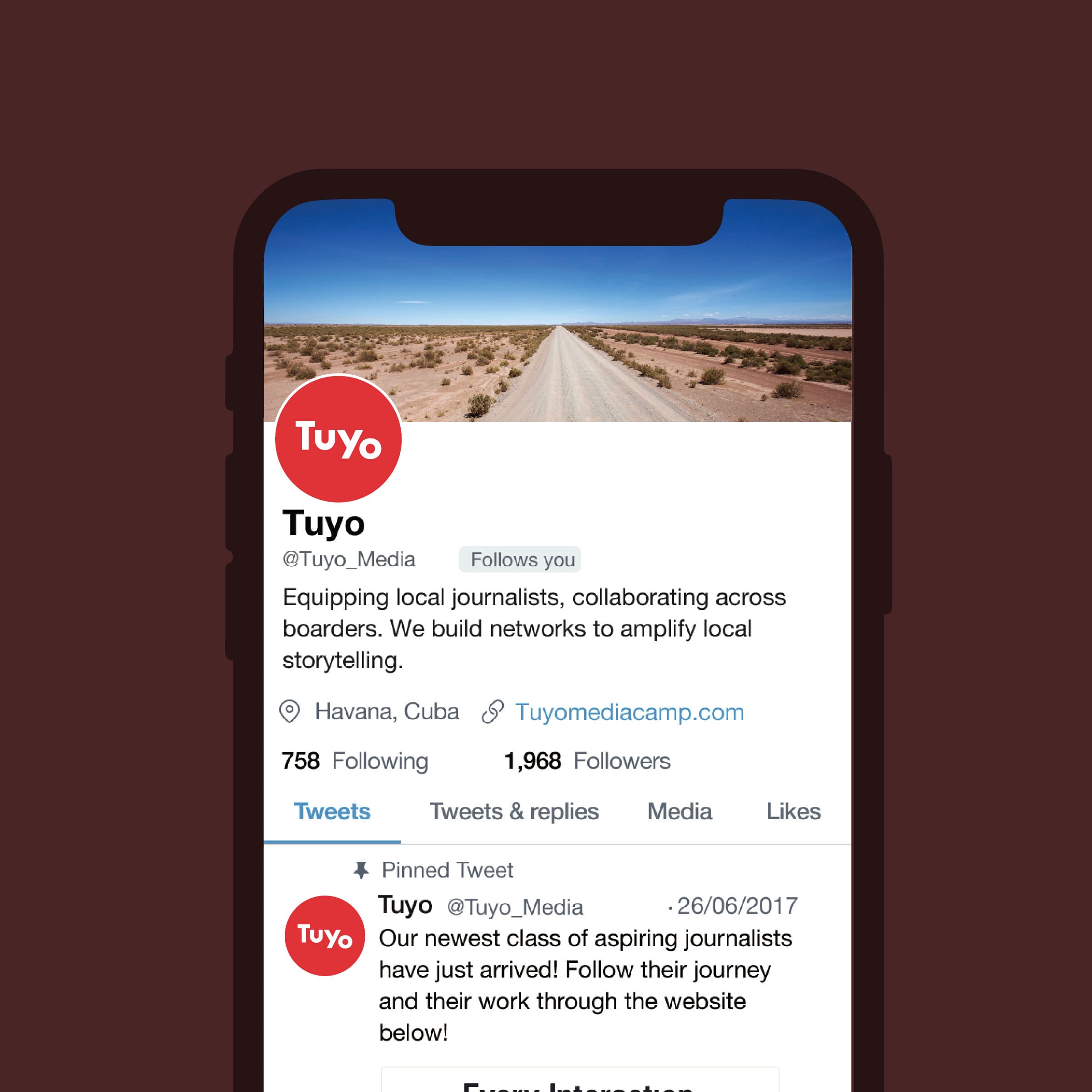 A smartphone displaying a Twitter profile for "Tuyo," an organization focused on equipping local journalists. The profile background image shows a desert landscape with a winding road. The tweet reads: "Our newest class of aspiring journalists have just arrived!.