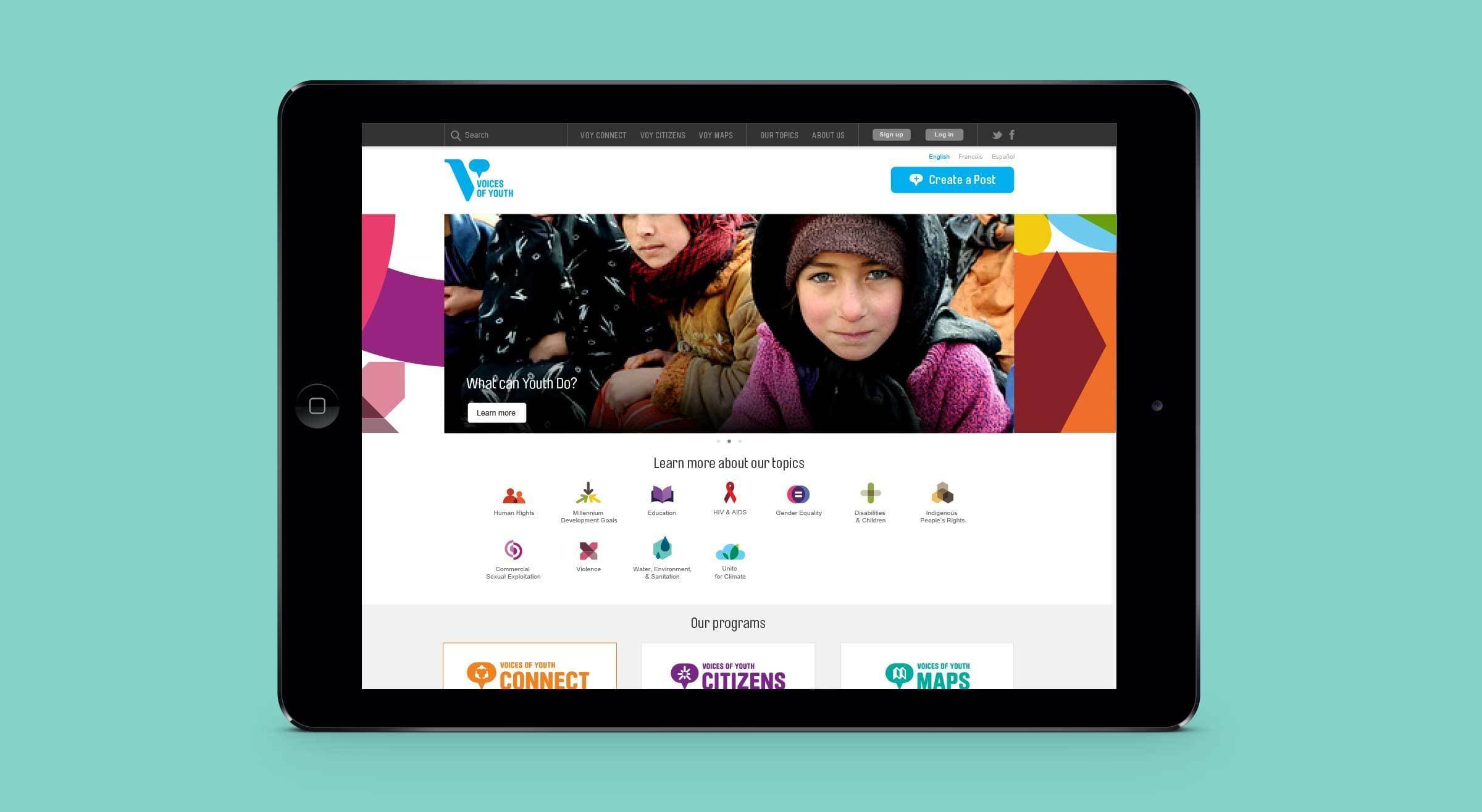 A tablet displaying a website with an image of a child dressed warmly and a banner saying, "Learn more about our topics." Various icons and sections are visible below, including options like "Connect," "Citizens," and "Maps." The background is teal blue.