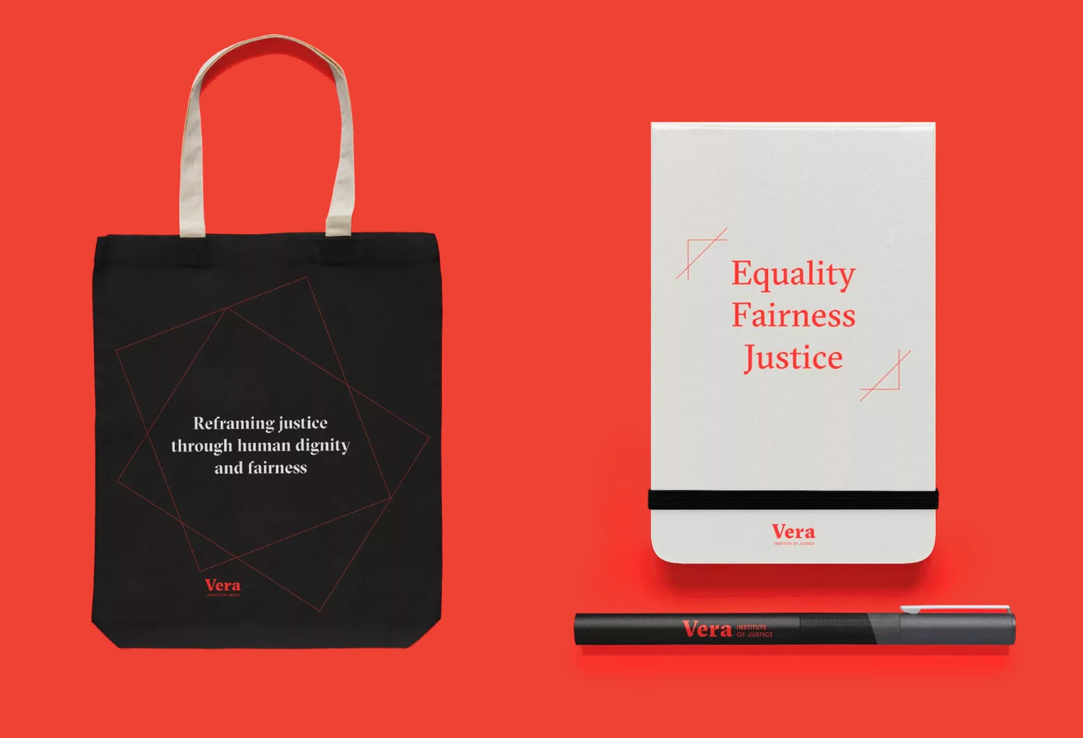 A black tote bag with the text "Reframing justice through human dignity and fairness" and "Vera" in red font. Beside it, a white notebook with "Equality Fairness Justice" in red, and "Vera" below, accompanied by a black pen with "Vera" in red on a bright red background.