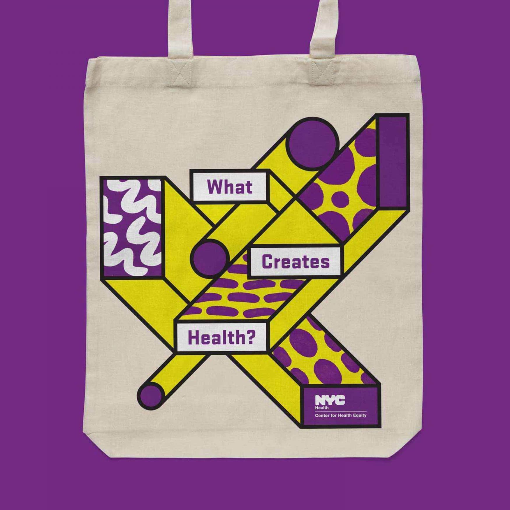 A beige tote bag with geometric shapes in yellow, purple, and white. The shapes form a collage with patterns and the text "What Creates Health?" in white boxes. At the bottom, a purple rectangle with the NYC Center for Health Equity logo. Background in purple.